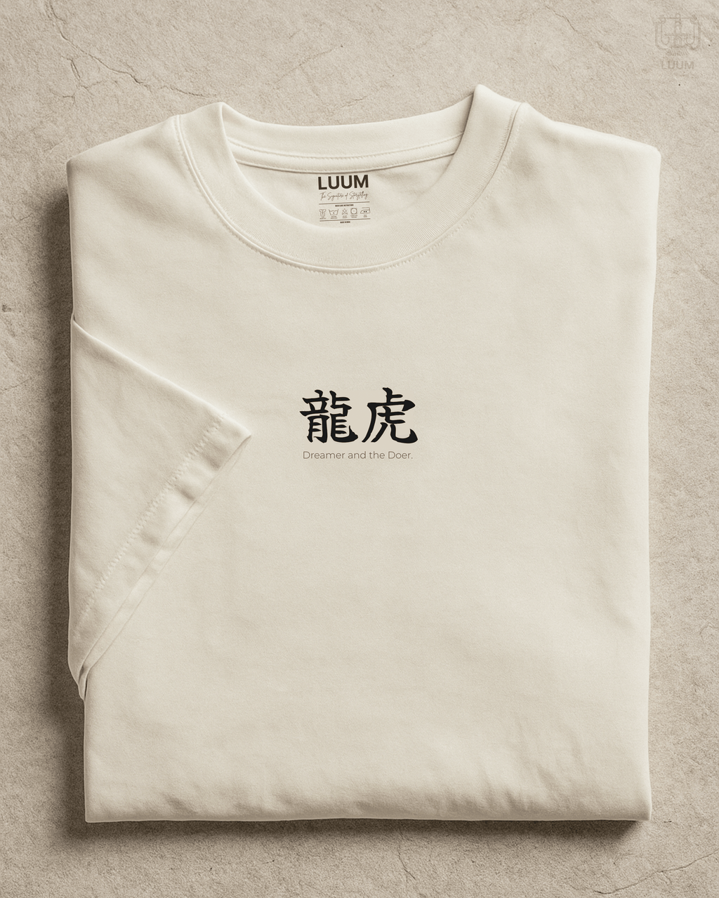 Folded view of LUUM’s “Dreamer and the Doer” off-white Supima t-shirt featuring dragon and tiger duality design. Part of Threadmark Collection. Belief. Woven and Worn.