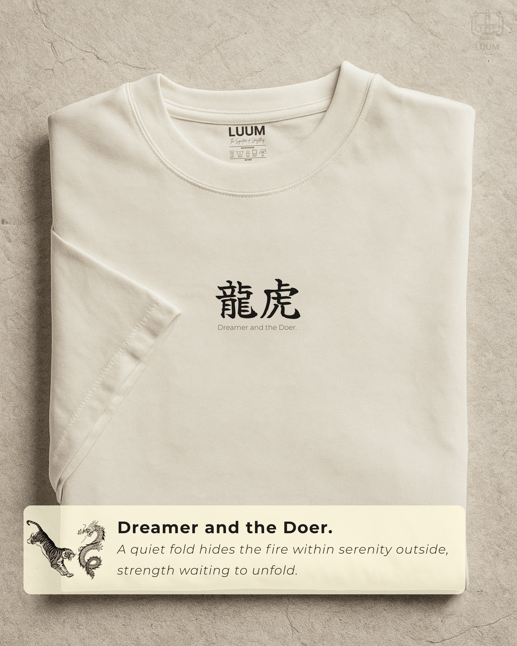Folded view of LUUM’s “Dreamer and the Doer” off-white Supima t-shirt featuring dragon and tiger duality design. The ultimate philosophy.  Part of Threadmark Collection. Belief. Woven and Worn.