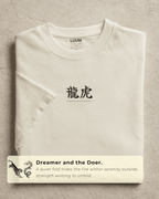Folded view of LUUM’s “Dreamer and the Doer” off-white Supima t-shirt featuring dragon and tiger duality design. The ultimate philosophy.  Part of Threadmark Collection. Belief. Woven and Worn.