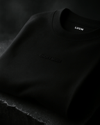 LUUM's Ghost Mode Close-up of black-on-black embroidery on Supima cotton. Part of Threadmark Collection. Belief. Woven and Worn.